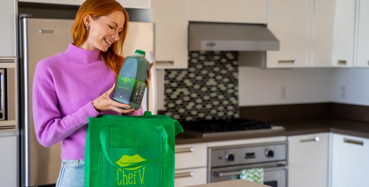 woman pulling 64 oz organic green drink bottle from a Chef V bag