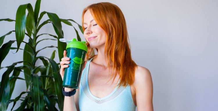 woman drinking organic green drink from a tumbler