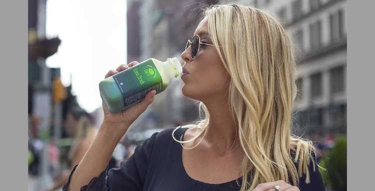 Veronica drinking green drink on a busy street
