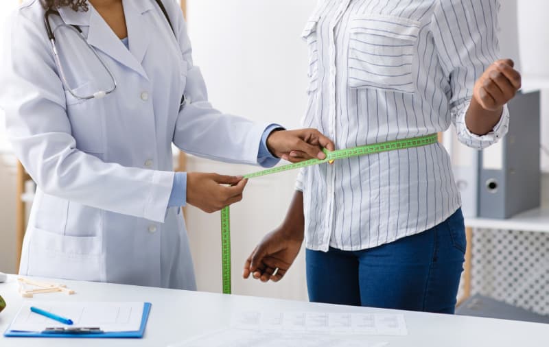 doctor measuring waist of patient