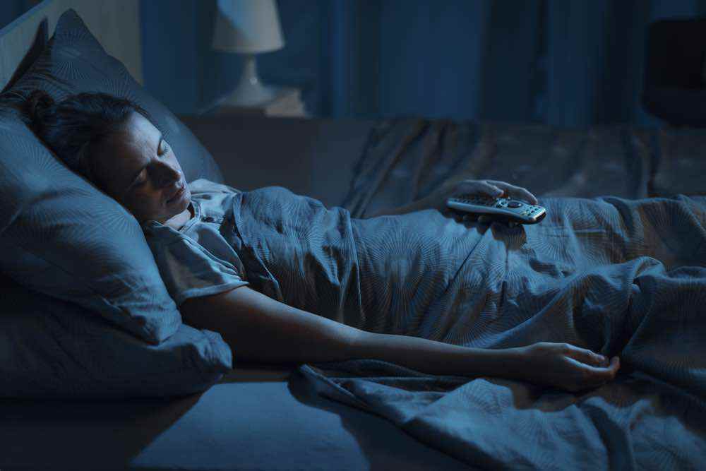 woman sleeping with remote in hand