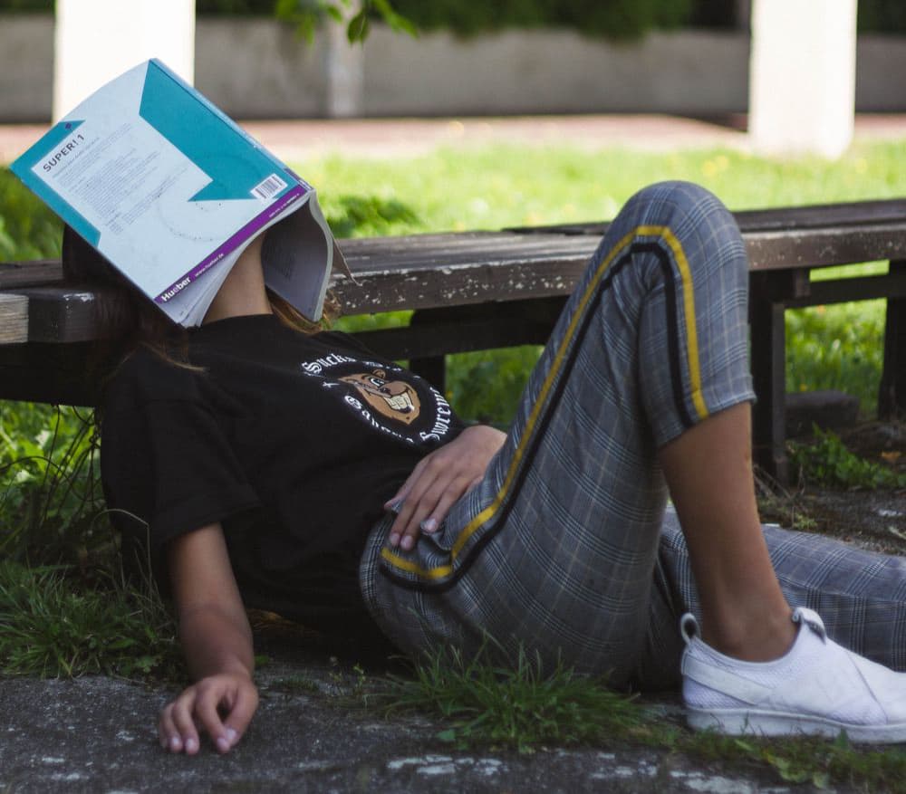 woman sleeping outside with book over face